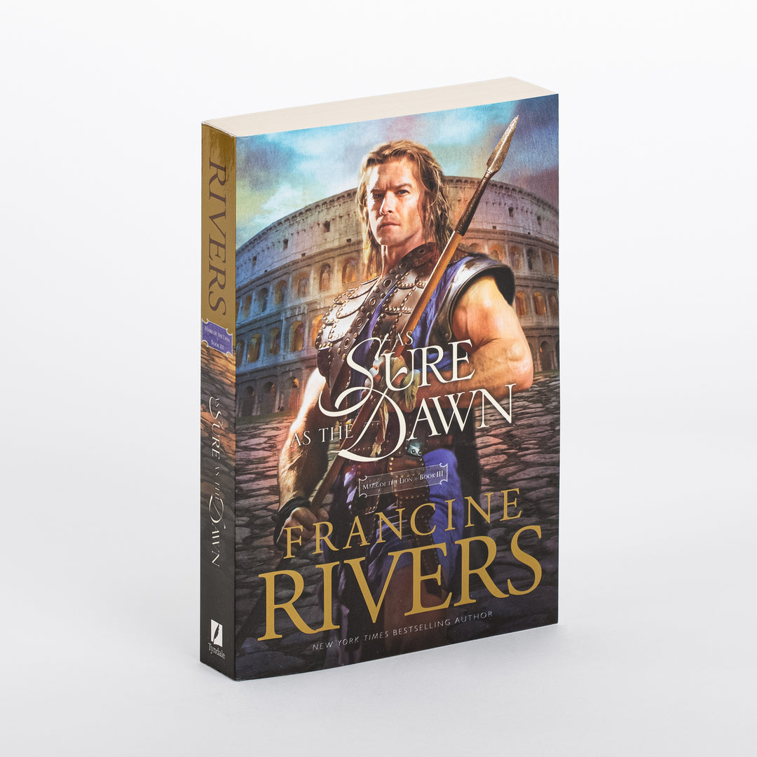 Paperback of As Sure as the Dawn (Mark of the Lion, Book 3) by Francine Rivers, angled to show the front cover and spine. The cover shows a bare-armed Roman warrior with long hair holding a spear before the Colosseum under a blue sky, with the title in white cursive script and the gold Francine Rivers byline below. The tan spine reads RIVERS and the title vertically, with a small purple Mark of the Lion Book III tag.