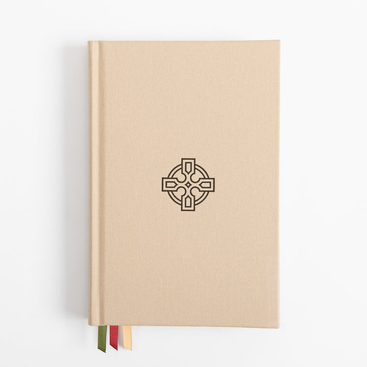 Straight-on view of the tan linen hardcover, its cover blank except for a black embossed Celtic cross centered on the front. Three ribbon markers - olive green, red, and gold - hang from the bottom edge.