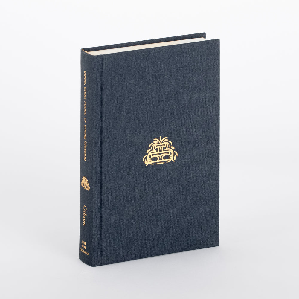 Angled shot of the hardcover book itself outside its slipcase: plain slate-blue cloth binding with a single small gold fountain emblem centered on the front cover, gold spine text reading 'Come, Thou Fount of Every Blessing / Gibson' above a Crossway logo, and three ribbon markers (cream, red, olive) draping from the bottom edge.