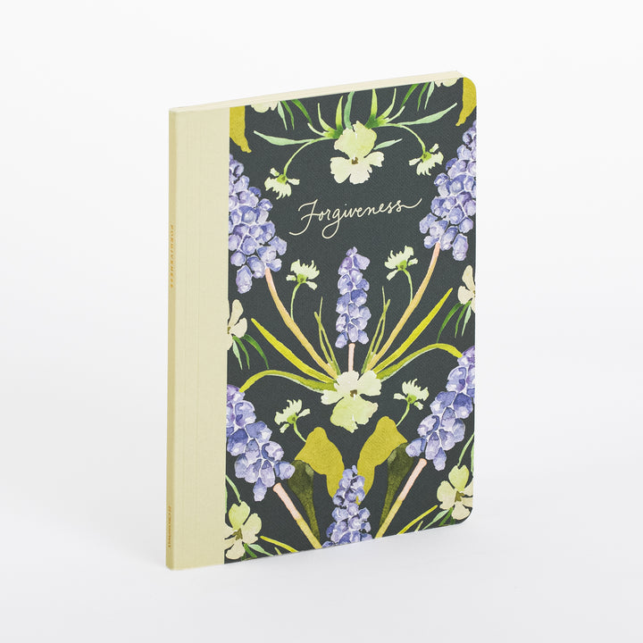 ESV Prayer Journal: 30 Days on Forgiveness shown at an angle, revealing its cream fabric spine and dark green cover illustrated with purple grape hyacinth blooms and pale yellow wildflowers, with &