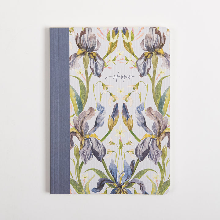 Front cover of the ESV Prayer Journal: 30 Days on Hope, laid flat. A symmetrical, mirrored watercolor pattern of purple, lavender, and blue iris flowers with gold centers covers the cream fabric, with &