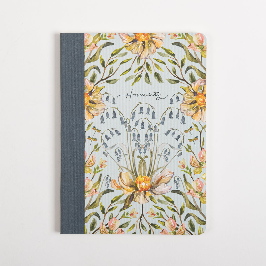 Flat, straight-on front cover of the Humility scripture journal with a light blue background, watercolor peach peonies, blue bellflowers, and dragonflies framing a cursive &