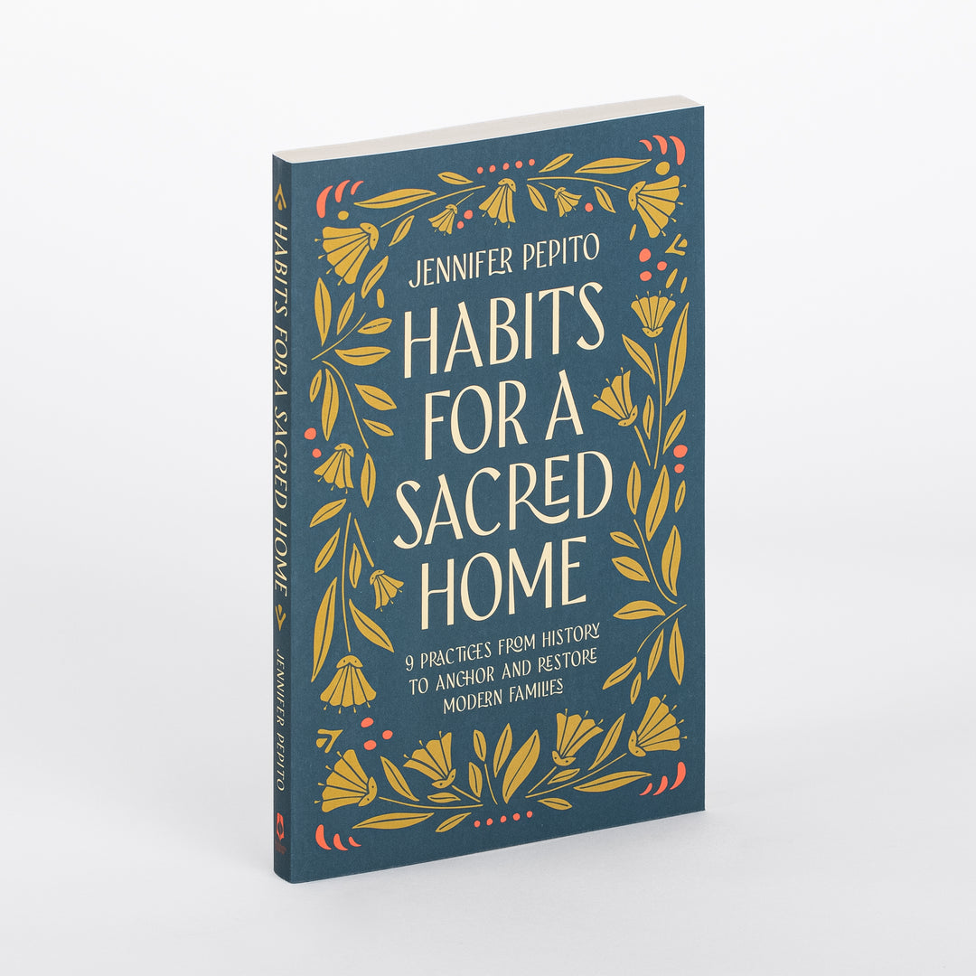 Angled three-quarter view of the paperback book Habits for a Sacred Home by Jennifer Pepito, showing its dark teal cover with gold floral border and the spine, which repeats the title vertically in cream lettering.