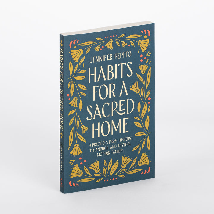 Angled three-quarter view of the paperback book Habits for a Sacred Home by Jennifer Pepito, showing its dark teal cover with gold floral border and the spine, which repeats the title vertically in cream lettering.