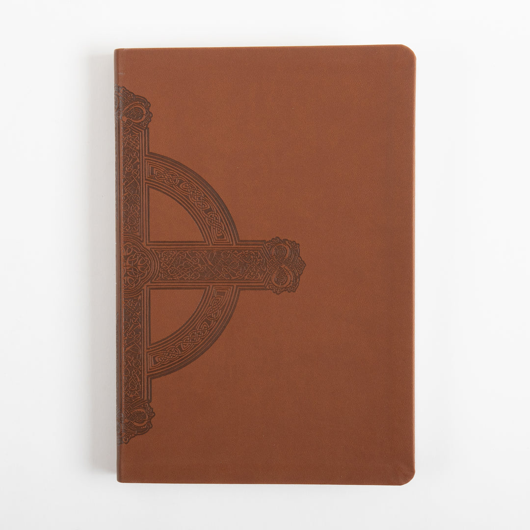 Front cover of the Bible lying flat, in warm brown leatherlike material with an embossed dark brown Celtic-style cross featuring intricate knotwork and scrollwork along the left edge, rounded corners, photographed against a plain white background.