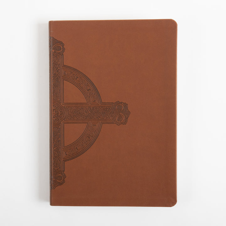 Front cover of the Bible lying flat, in warm brown leatherlike material with an embossed dark brown Celtic-style cross featuring intricate knotwork and scrollwork along the left edge, rounded corners, photographed against a plain white background.