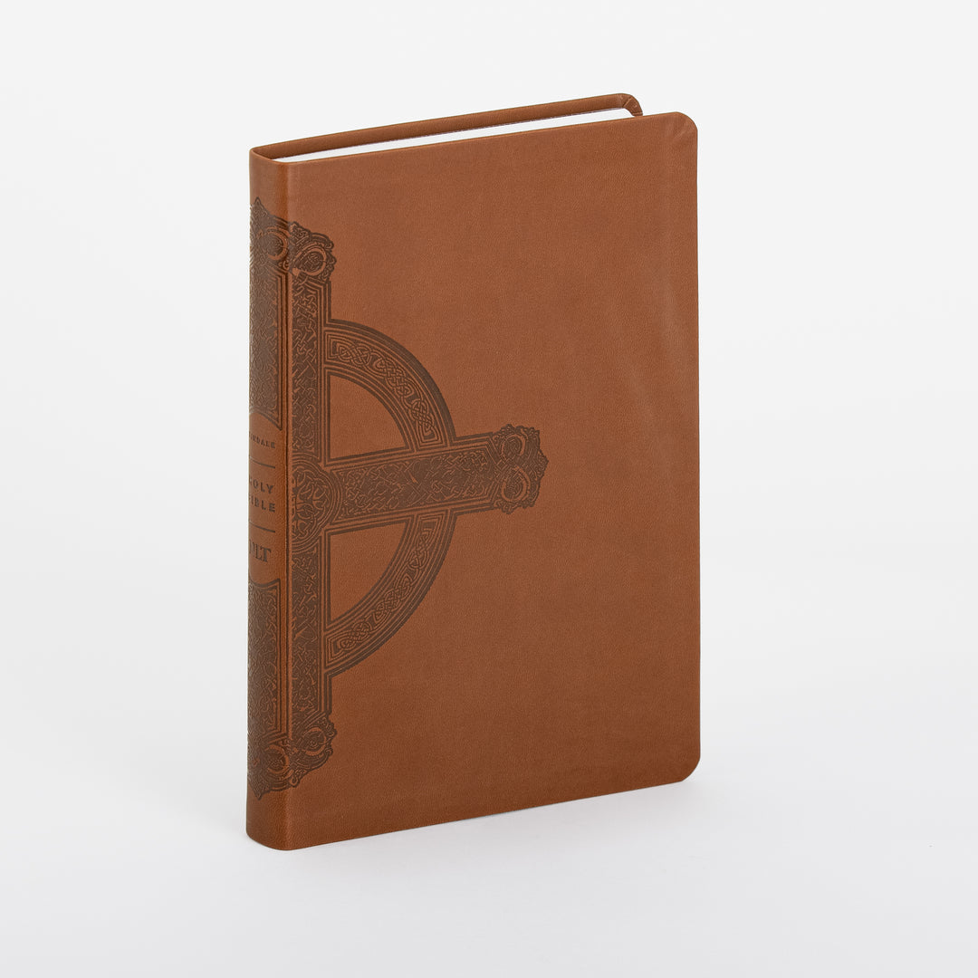 NLT Large Print Premium Value Thinline Bible in brown leatherlike cover, shown at a three-quarter angle with the spine visible, featuring an embossed ornate Celtic-style cross with knotwork detailing and gold-brown lettering reading Holy Bible NLT on the spine.