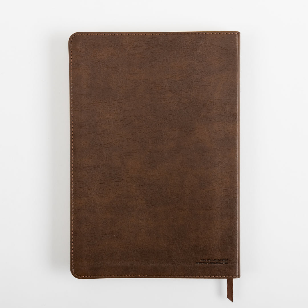 Back cover of the rustic brown leatherlike NLT Large Print Thinline Reference Bible, viewed flat from above, showing the leather grain texture, a small embossed line of text in the lower right corner, and the ribbon marker.