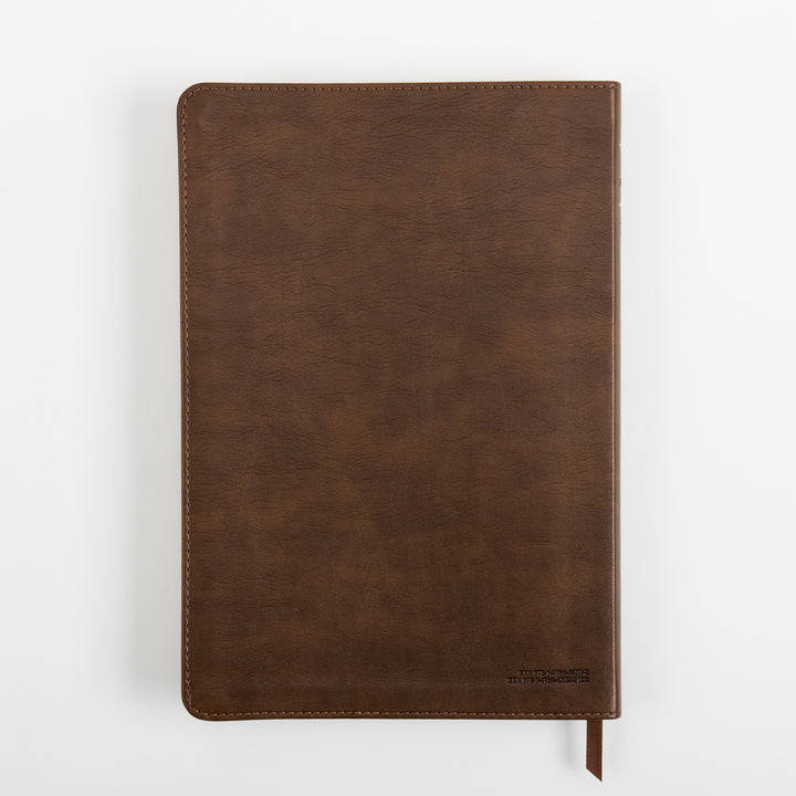 Back cover of the rustic brown leatherlike NLT Large Print Thinline Reference Bible, viewed flat from above, showing the leather grain texture, a small embossed line of text in the lower right corner, and the ribbon marker.