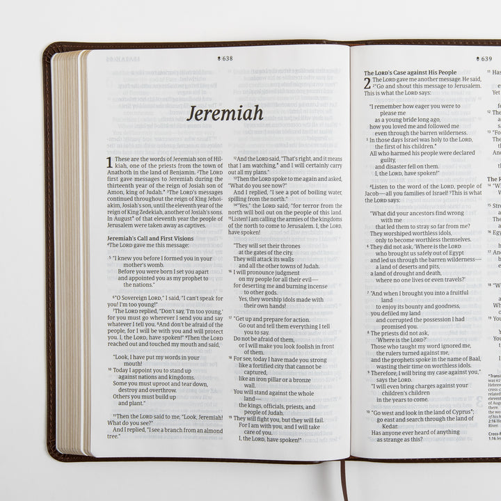 Open Bible spread showing the large-print italic title page for the book of Jeremiah with chapter 1 and the start of chapter 2, a brown ribbon marker hanging from the spine, and cross-references at the bottom of the page.