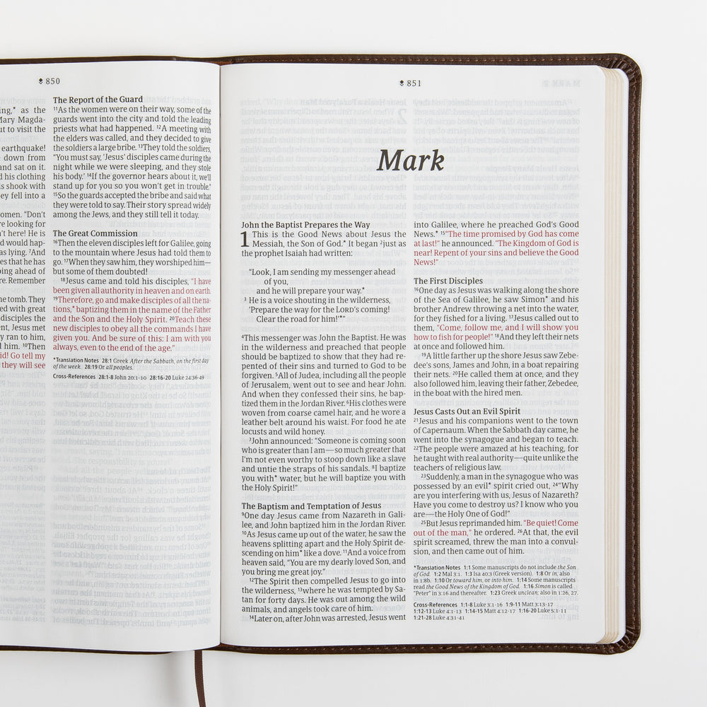 Open Bible spread showing the end of Matthew and the title page for the Gospel of Mark, with the words of Jesus printed in red, large-print two-column text, and translation notes and cross-references at the bottom.
