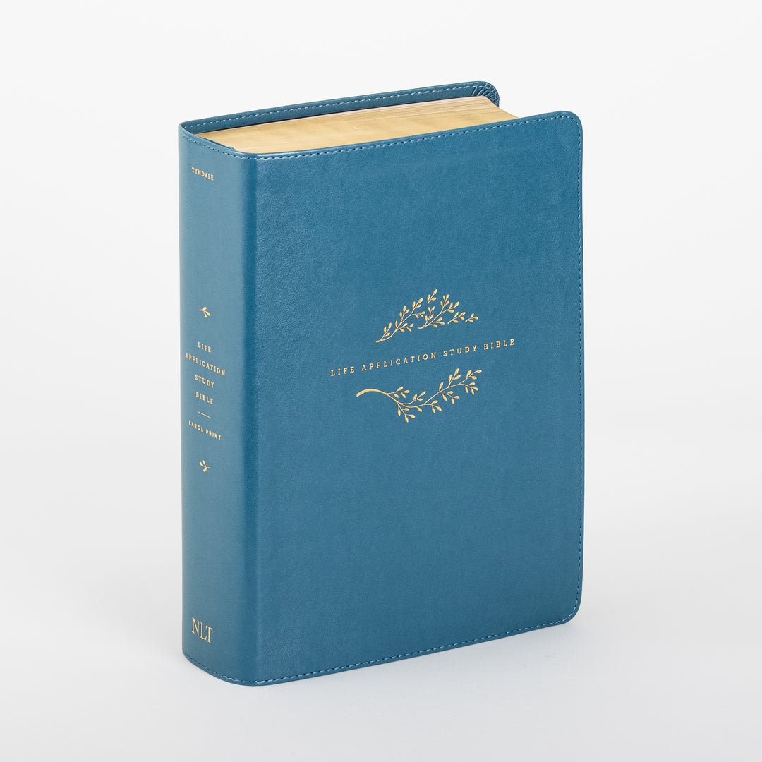 Teal leatherlike NLT Life Application Study Bible standing upright at an angle, showing the front cover and spine with gold vine embossing, gold-edged pages, and 'Life Application Study Bible Large Print' lettering on the spine.