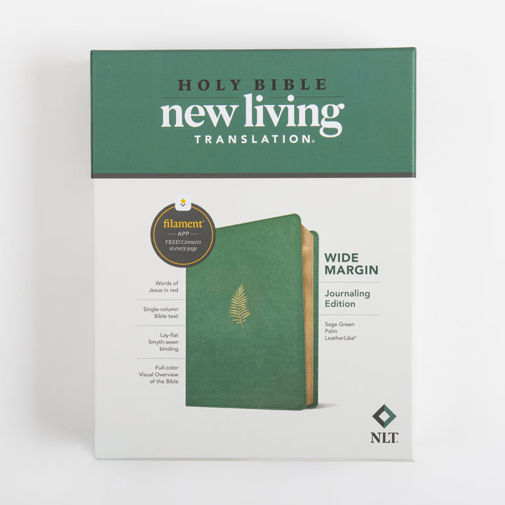 Front of the retail box for the NLT Wide Margin Bible, Filament Enabled, showing the Holy Bible New Living Translation logo, a Filament app badge, a feature list including words of Jesus in red and lay-flat Smyth-sewn binding, and the sage green palm leatherlike Bible standing beside the box, labeled Wide Margin Journaling Edition.