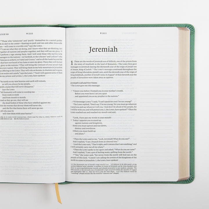 Open interior spread of the NLT Wide Margin Bible showing the end of Isaiah 66 on the left page and the title page of Jeremiah with the start of chapter 1 on the right, bordered by a wide blank ruled margin and a tan ribbon marker at the gutter.