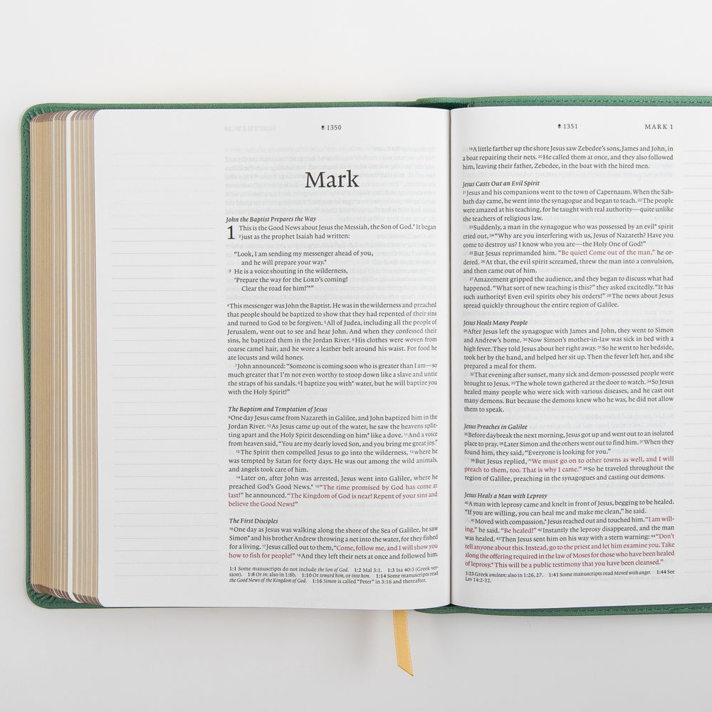 Open interior spread of the NLT Wide Margin Bible showing the Gospel of Mark title page and the start of chapter 1 on the left page and the continuation of Mark 1 on the right, with the words of Jesus printed in red and wide blank ruled margins on both sides for handwritten notes.