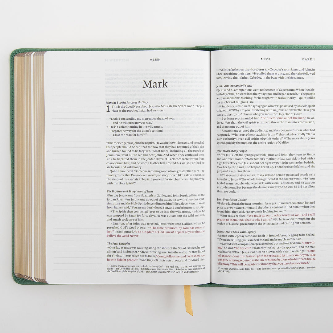 Open interior spread of the NLT Wide Margin Bible showing the Gospel of Mark title page and the start of chapter 1 on the left page and the continuation of Mark 1 on the right, with the words of Jesus printed in red and wide blank ruled margins on both sides for handwritten notes.