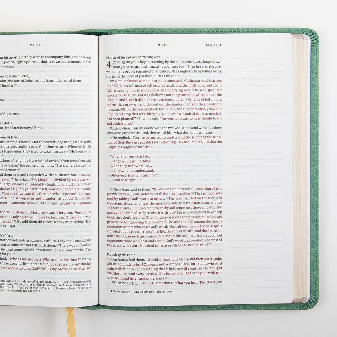 Top-down view of the NLT Wide Margin Bible open to Mark 3-4, including the Parable of the Farmer Scattering Seed, with the words of Jesus printed in red and a wide blank ruled margin along the right page for handwritten notes.