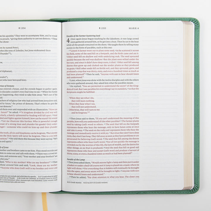 Top-down view of the NLT Wide Margin Bible open to Mark 3-4, including the Parable of the Farmer Scattering Seed, with the words of Jesus printed in red and a wide blank ruled margin along the right page for handwritten notes.