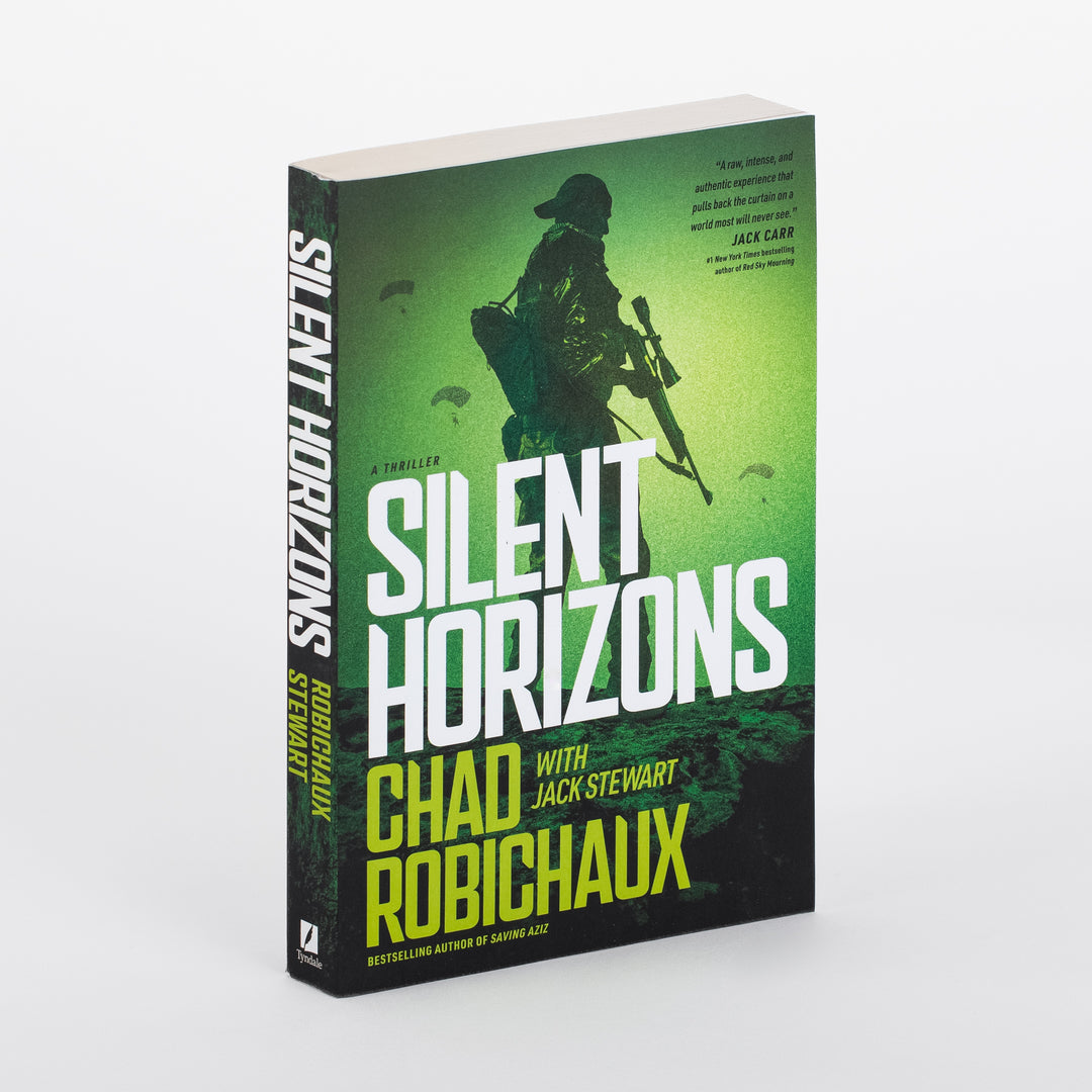 Close-up angled view of the 'Silent Horizons' paperback cover: a soldier's dark silhouette in tactical gear and cap, carrying a backpack and rifle, set against a glowing green sky with two parachutes descending in the background. A pull quote from Jack Carr, #1 New York Times bestselling author of Red Sky Mourning, reads 'A raw, intense, and authentic experience that pulls back the curtain on a world most will never see.'
