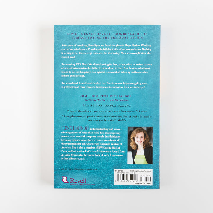 Back cover of Sunrise Reef by Irene Hannon on a teal textured background, with white body text giving the synopsis about barista Bren Ryan and CPA Noah Ward in Hope Harbor, a review blurb for Sandcastle Inn, an author photo of Irene Hannon in a black jacket, the Revell publisher logo, and a barcode with price and ISBN.