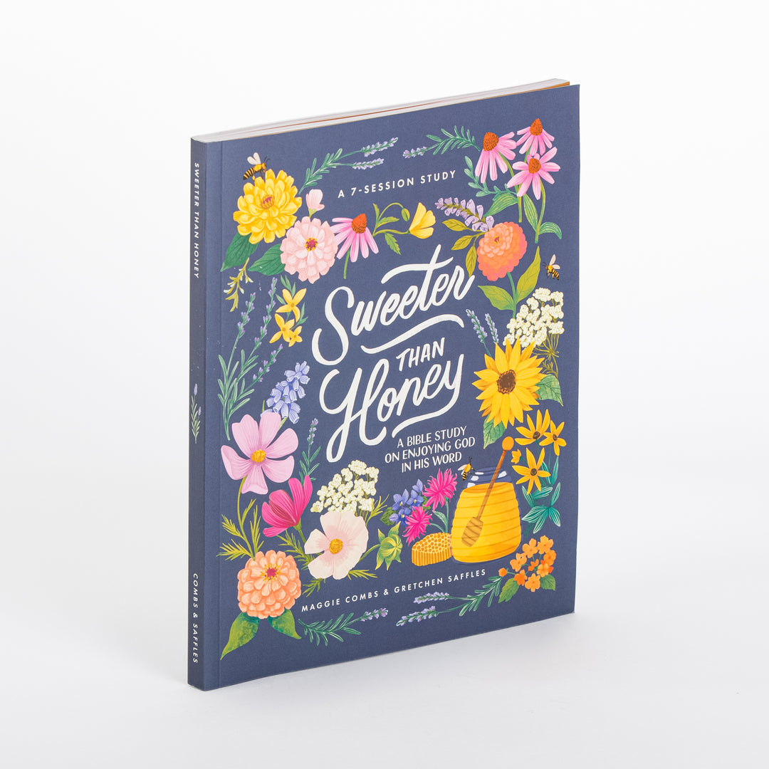 Sweeter Than Honey: A Bible Study on Enjoying God in His Word, shown at an angle. The navy blue hardcover is bordered with hand-painted flowers (sunflowers, pink coneflowers, zinnias, lavender) and a honey pot with dripping dipper and bees, with the title in white hand-lettered script and 'A 7-Session Study' at top; authors Maggie Combs & Gretchen Saffles at bottom.