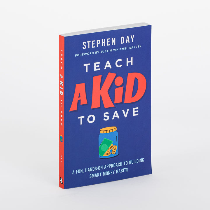 Angled product shot of the paperback book Teach a Kid to Save by Stephen Day, foreword by Justin Whitmel Earley. Navy blue cover with bold red &
