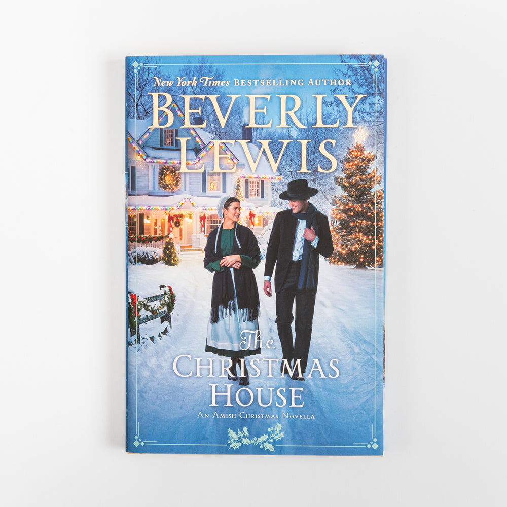 Front cover of The Christmas House, an Amish Christmas novella by Beverly Lewis, showing an Amish couple walking hand in hand along a snowy path past a decorated farmhouse and lit Christmas tree at dusk.
