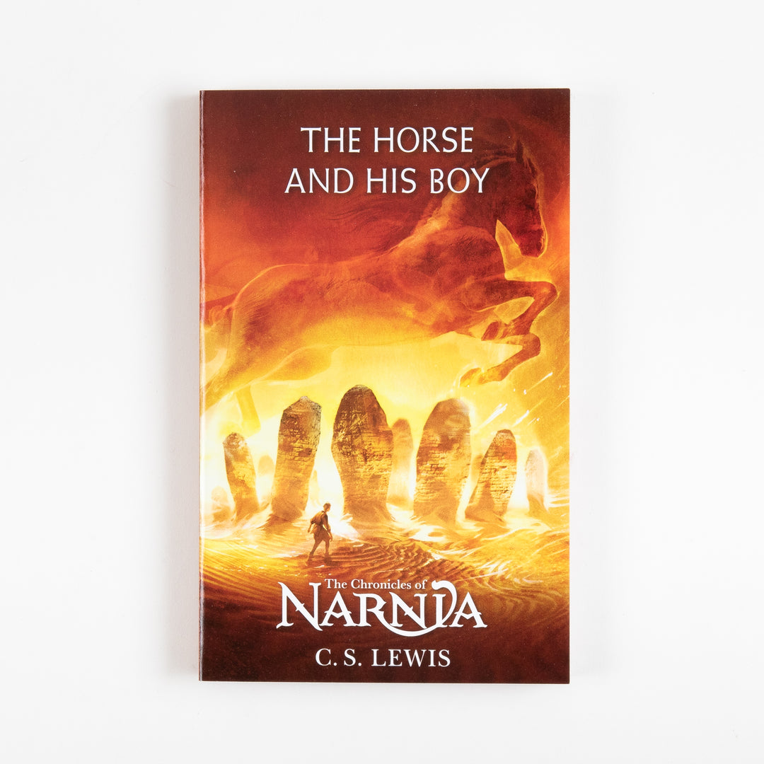 Front cover of The Horse and His Boy, book three of The Chronicles of Narnia by C.S. Lewis, showing a fiery orange desert scene with a running horse silhouette above ancient standing stones and a lone traveler.