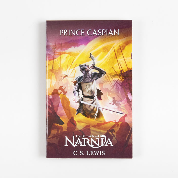 Front cover of Prince Caspian, book four of The Chronicles of Narnia by C.S. Lewis, showing an armored knight blowing a horn amid a battle scene rendered in gold, purple, and magenta tones.
