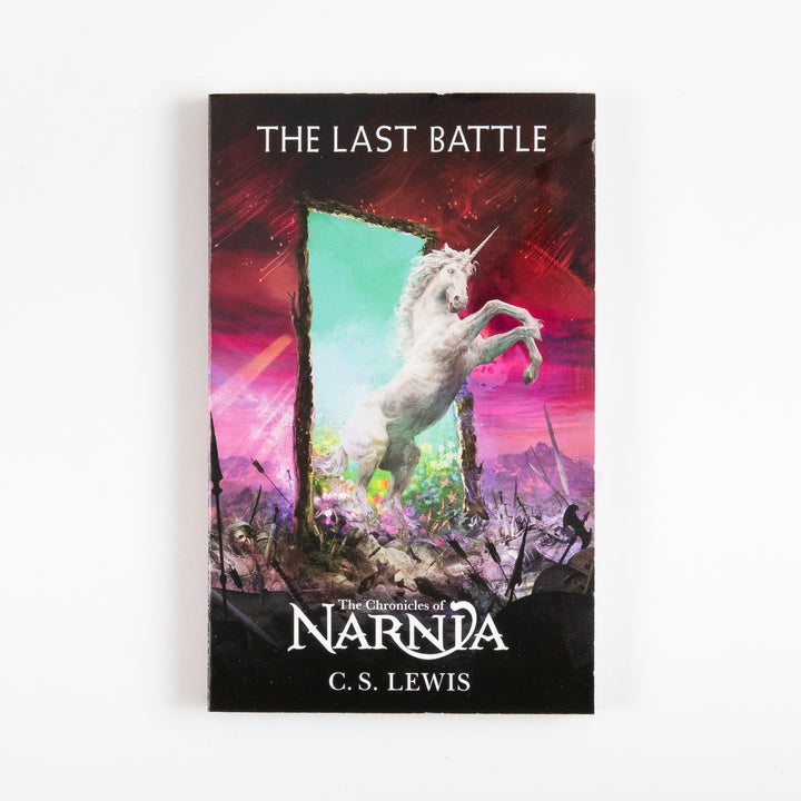Front cover of The Last Battle, book seven of The Chronicles of Narnia by C.S. Lewis, showing a white unicorn rearing before a glowing green doorway set against a fiery red battlefield sky.