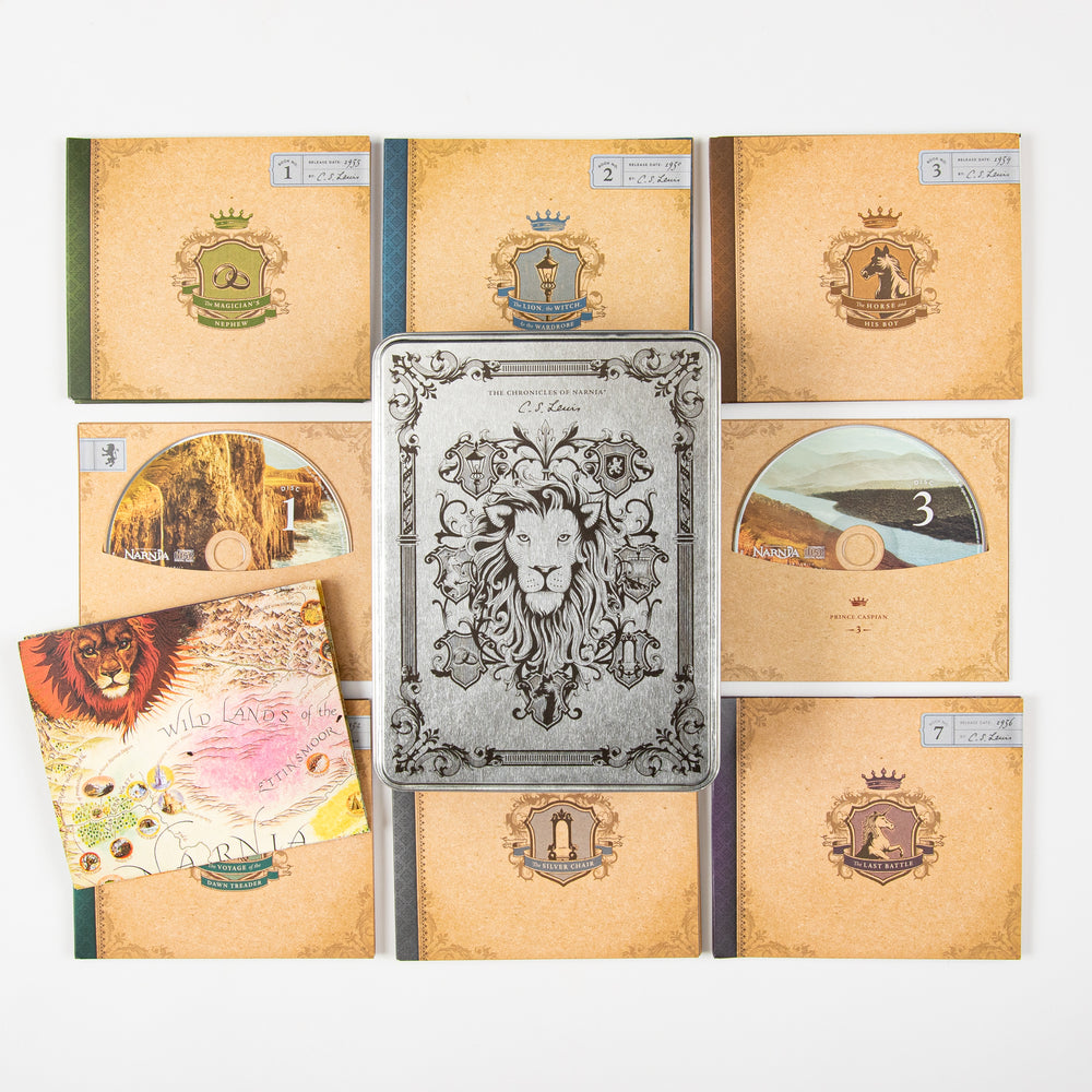 Interior contents of the Narnia Radio Theatre tin laid flat: seven kraft-paper book-style CD sleeves each with a colored crest (books 1, 2, 3, and 7 shown face up), two discs numbered 1 and 3 resting beside a folded illustrated map titled 'Wild Lands of the Ethenmoor,' and the embossed silver lion lid in the center.