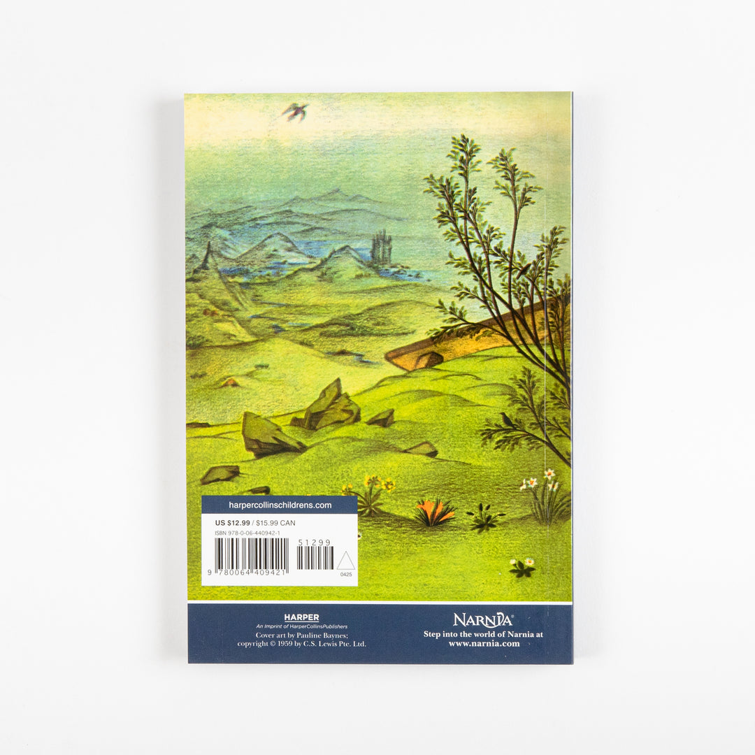 Back cover of the full-color paperback edition of The Lion, the Witch and the Wardrobe, showing a green hillside landscape with a stone bridge, shrubs, and a bird flying overhead, with a price sticker and barcode.