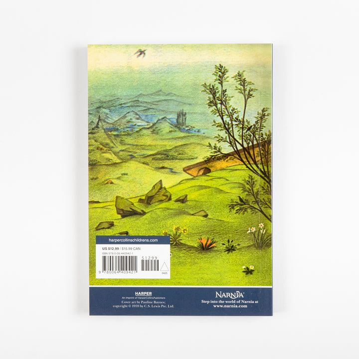 Back cover of the full-color paperback edition of The Lion, the Witch and the Wardrobe, showing a green hillside landscape with a stone bridge, shrubs, and a bird flying overhead, with a price sticker and barcode.