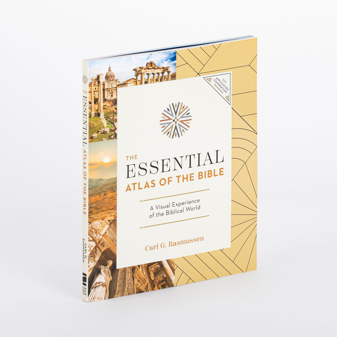 Three-quarter angled view of 'The Essential Atlas of the Bible' hardcover showing both the front cover and spine, with the gold patterned cover, cream title panel, and the photo collage of Roman ruins and desert scenery wrapping around the spine, where the title and author Carl G. Rasmussen appear vertically.