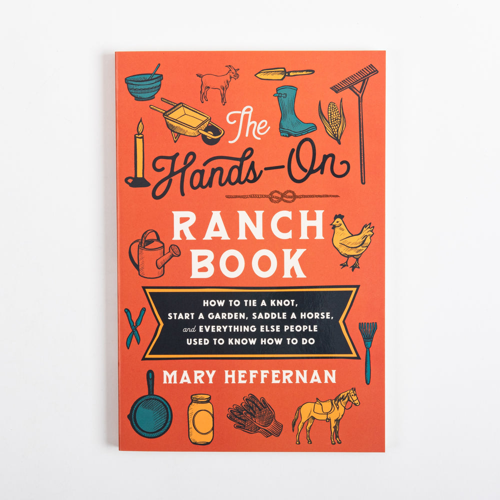 Front cover of The Hands-On Ranch Book by Mary Heffernan, flat-on view: orange cover with hand-drawn icons of a goat, chicken, saddled horse, wheelbarrow, rain boots, corn, rake, candle, watering can, skillet, mason jar, and gloves surrounding the navy-and-cream title and subtitle.