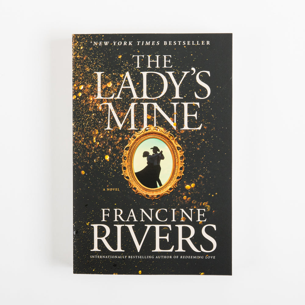 Front cover of the paperback novel The Lady's Mine by Francine Rivers, photographed straight-on. The black cover is speckled with gold paint flecks around a center oval gold frame with the black silhouette of a couple dancing, the man in a wide-brimmed hat. White text reads 'New York Times Bestseller' at top, the title 'The Lady's Mine,' 'A Novel' beneath the frame, and 'Francine Rivers' in large letters near the bottom.