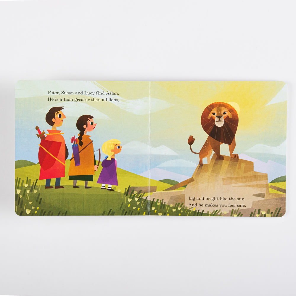 Interior spread from the board book showing Peter, Susan, and Lucy standing on a green hillside looking toward Aslan, a golden lion glowing in sunlight atop a rocky outcrop. Text reads 'Peter, Susan and Lucy find Aslan. He is a Lion greater than all lions, big and bright like the sun. And he makes you feel safe.'