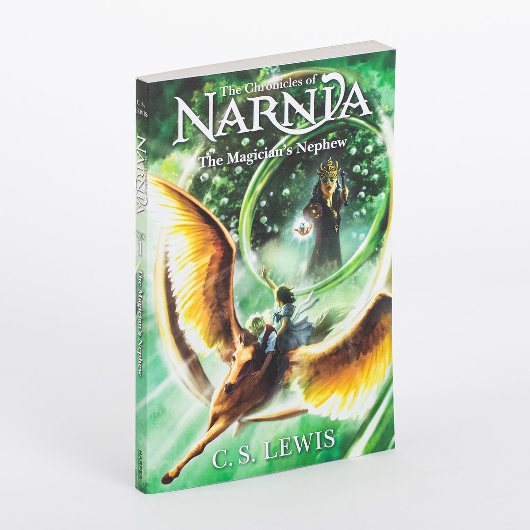Paperback of The Chronicles of Narnia: The Magician's Nephew by C.S. Lewis shown at an angle, revealing the spine and front cover art of two children riding a winged horse toward a glowing green portal where a witch queen holds a glowing orb.