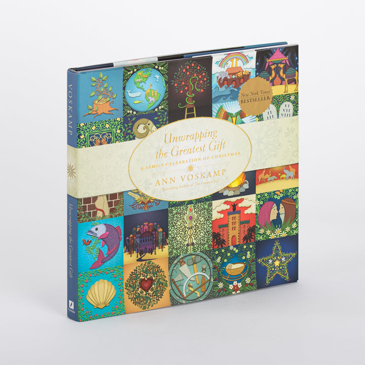 Three-quarter angle view of the hardcover Unwrapping the Greatest Gift: A Family Celebration of Christmas by Ann Voskamp, standing upright with its spine reading VOSKAMP and the same colorful folk-art icon quilt cover design wrapping around the front, including the New York Times Bestseller seal.