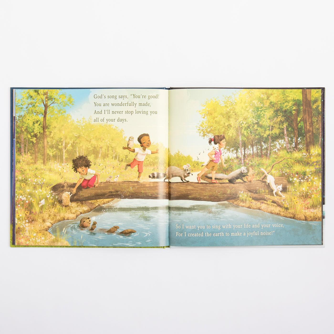 Open book showing a colorful illustration of children and animals by a creek in a forest.