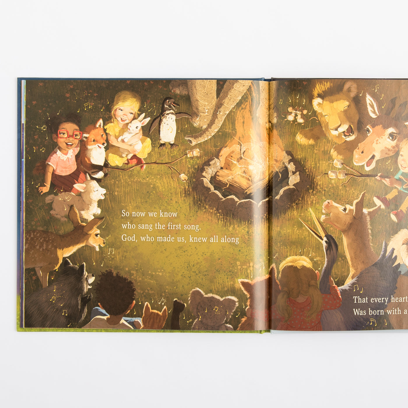 Open book with illustrations of children and animals around a campfire